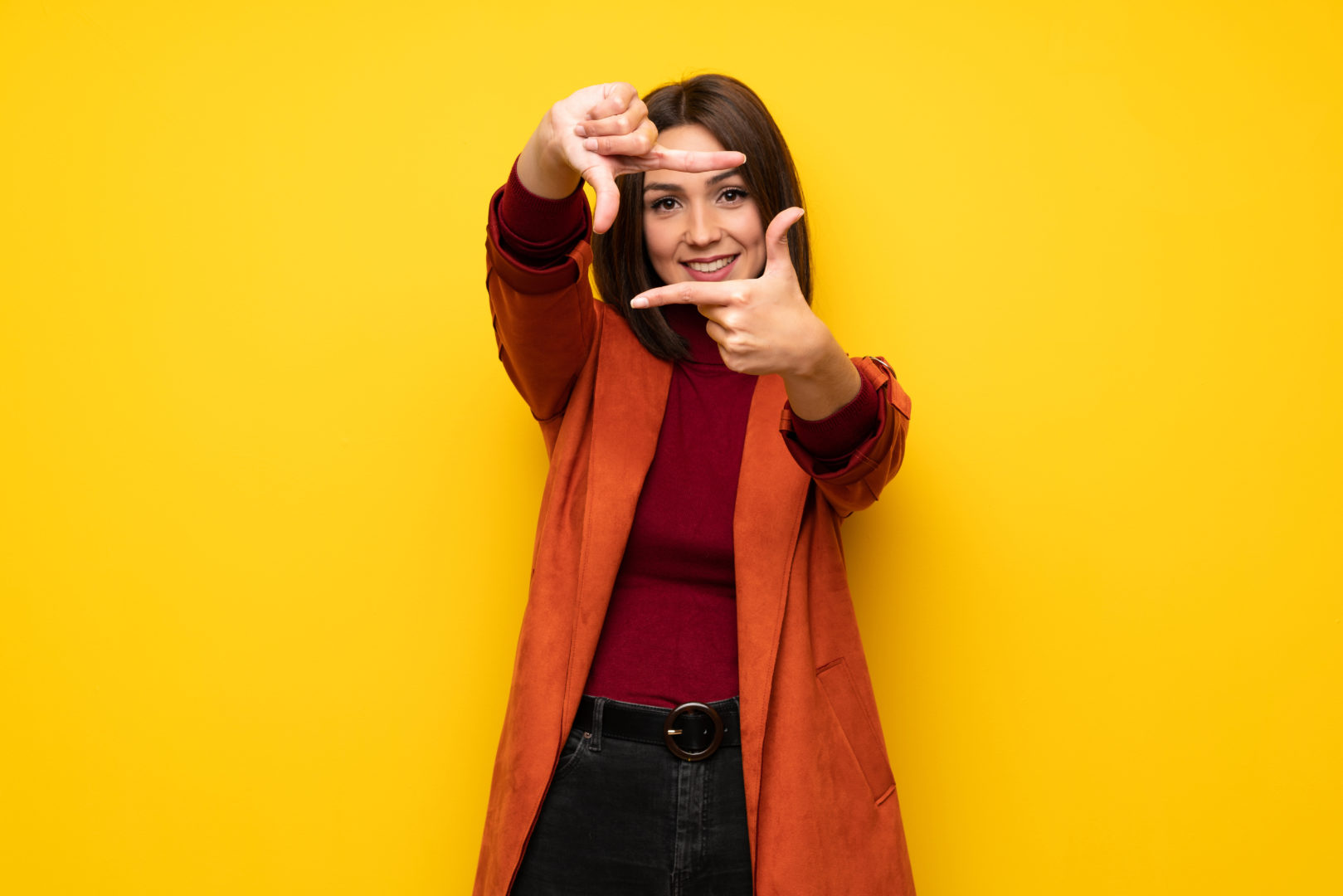 Young woman with coat focusing face. Framing symbol